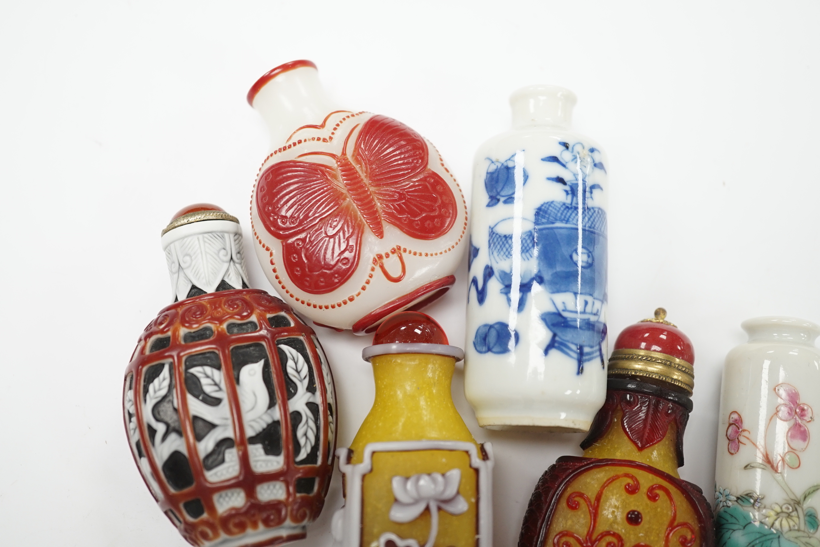 Four Chinese overlaid glass snuff bottles and two Chinese porcelain snuff bottles, three with stoppers, largest 9cm high